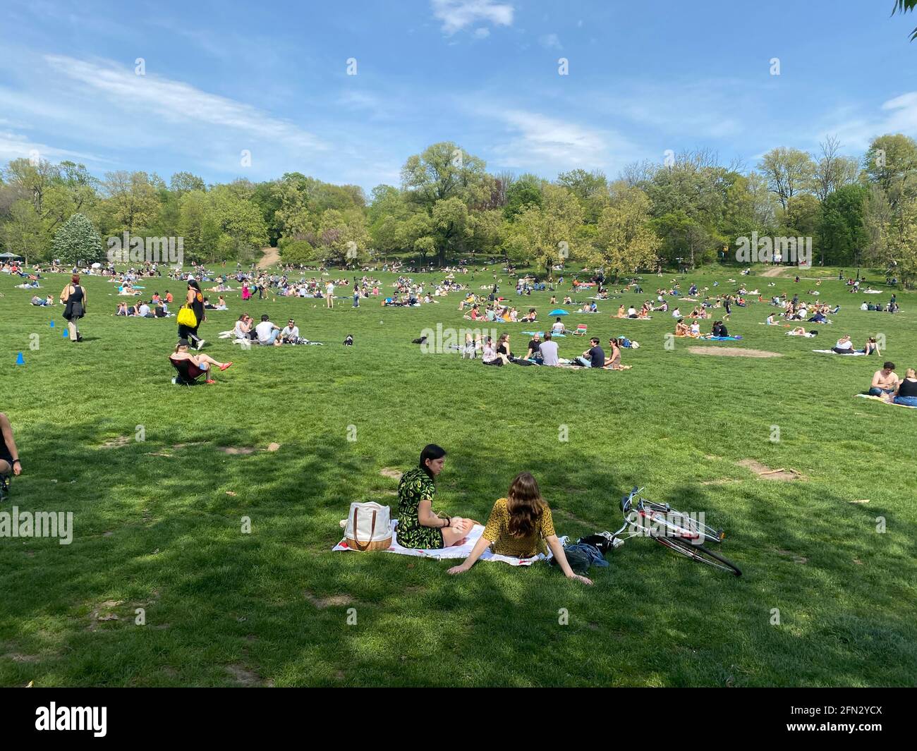 Gruppen von Menschen, die sich gesellschaftlich distanzieren und einen warmen Frühlingstag im Prospect Park genießen, über ein Jahr lang in die Covid-19-Pandemie in Brooklyn, New York. Stockfoto