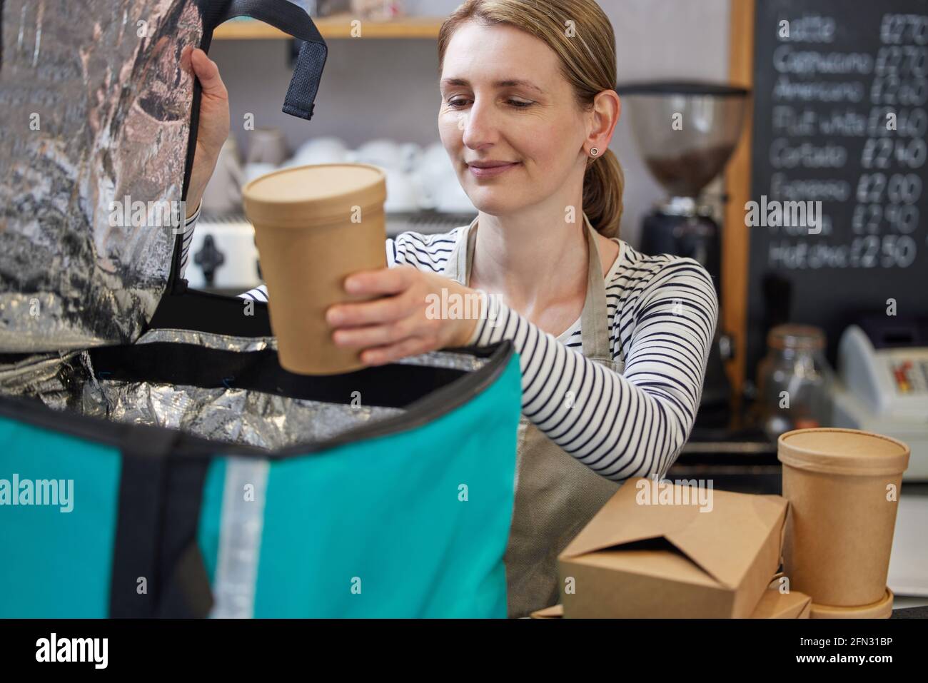 Weibliche Restaurantarbeiterin Verpackung Isolierte Tasche Für Takeaway Food Home Lieferung Stockfoto