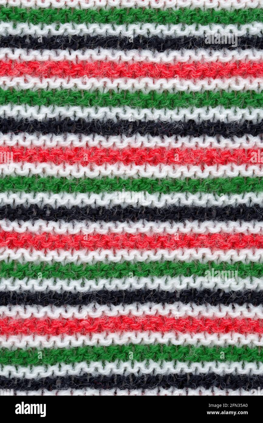 Nahaufnahme von Hand gestricktem Wollmuster in rot, weiß, schwarz und grün. Stockfoto