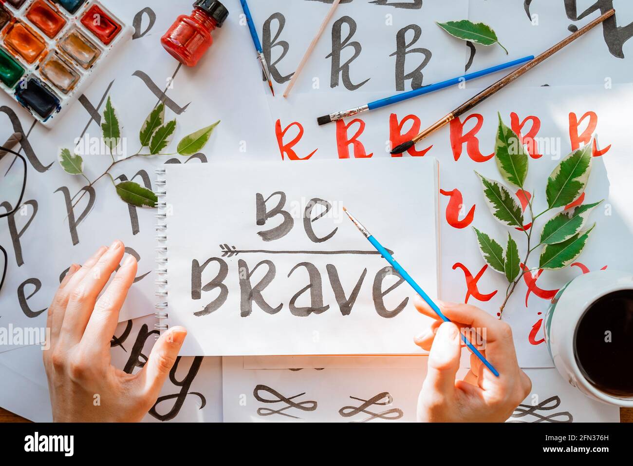 Overhead-Ansicht auf männlichen Mann Hände Kalligraphie Blätter, Schreibfedern, Papier, Tinte rote Stifte.Handwerk, Hobby. Lettering Workshop.Flat Lay Motivationsschreiben Worte Quo Stockfoto