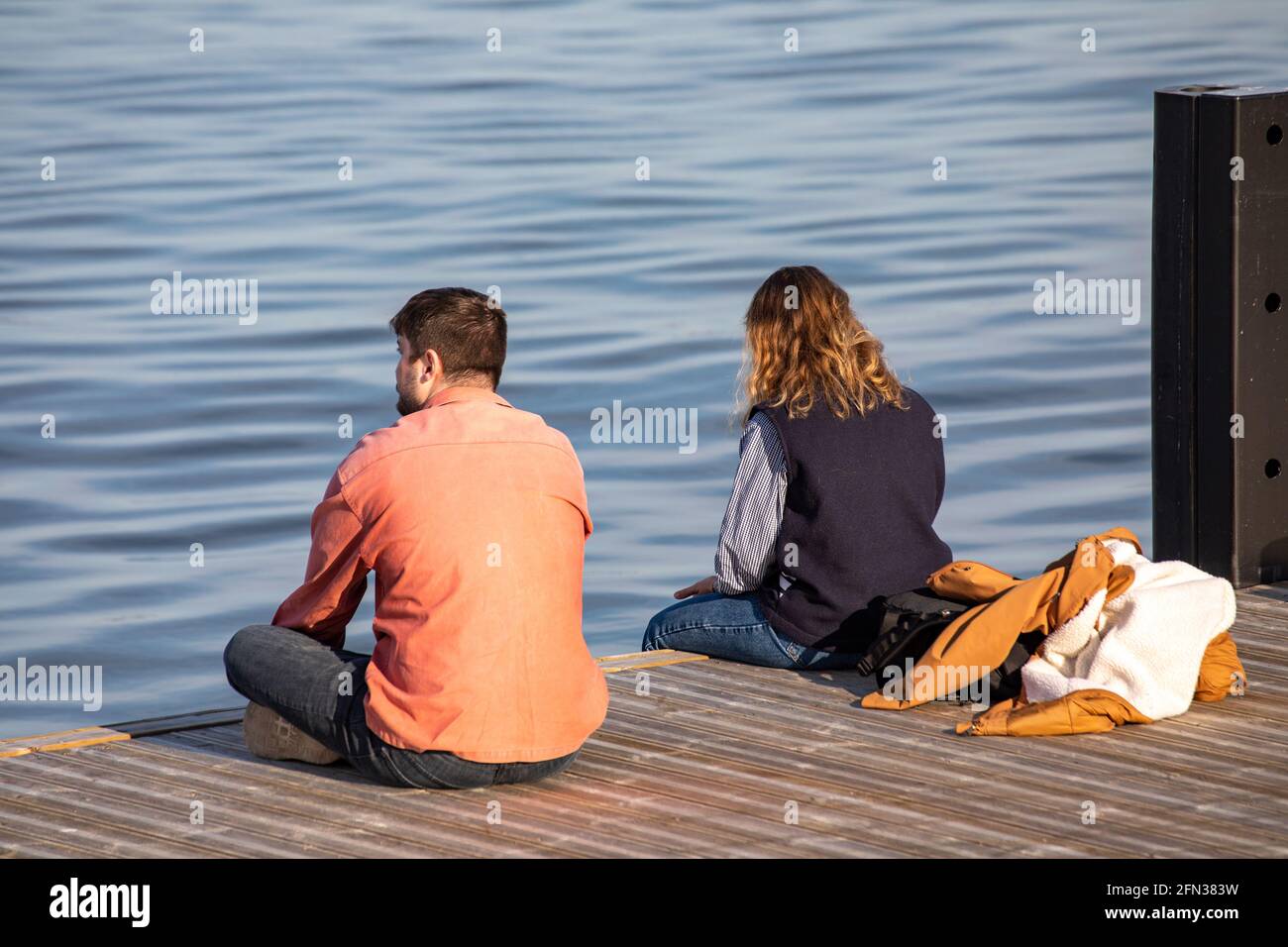 Junger Mann und junge Frau sitzen auf dem Steg oder Pier vorbei Das Meer Stockfoto