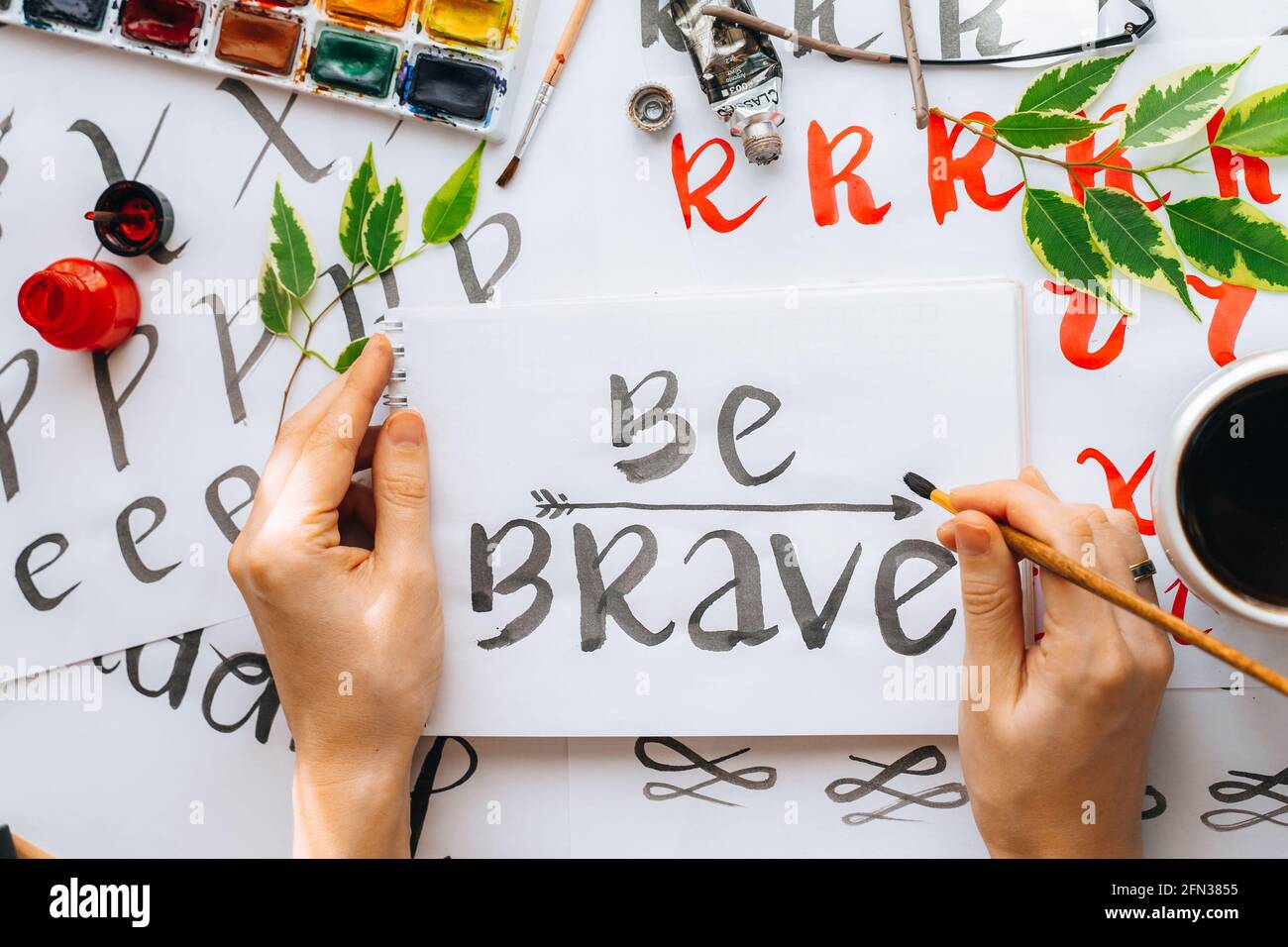 Overhead-Ansicht auf männlichen Mann Hände Kalligraphie Blätter, Schreibfedern, Papier, Tinte rote Stifte.Handwerk, Hobby. Lettering Workshop.Flat Lay Motivationsschreiben Worte Quo Stockfoto
