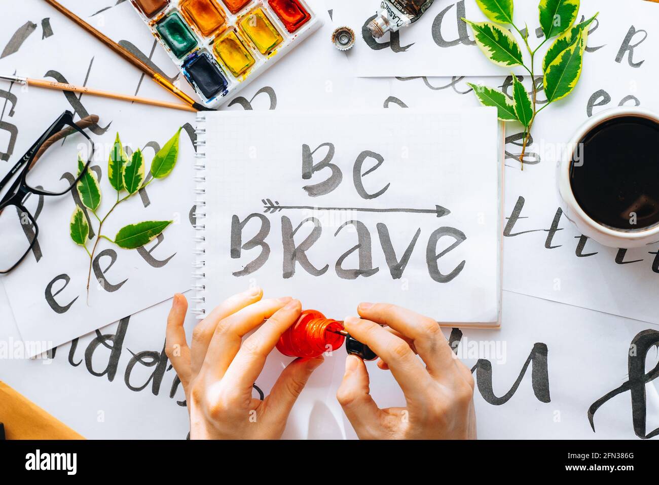 Overhead-Ansicht auf männlichen Mann Hände Kalligraphie Blätter, Schreibfedern, Papier, Tinte rote Stifte.Handwerk, Hobby. Lettering Workshop.Flat Lay Motivationsschreiben Worte Quo Stockfoto