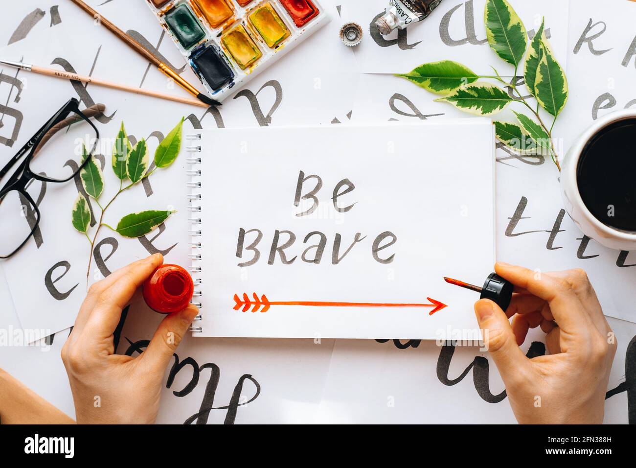 Overhead-Ansicht auf männlichen Mann Hände Kalligraphie Blätter, Schreibfedern, Papier, Tinte rote Stifte.Handwerk, Hobby. Lettering Workshop.Flat Lay Motivationsschreiben Worte Quo Stockfoto