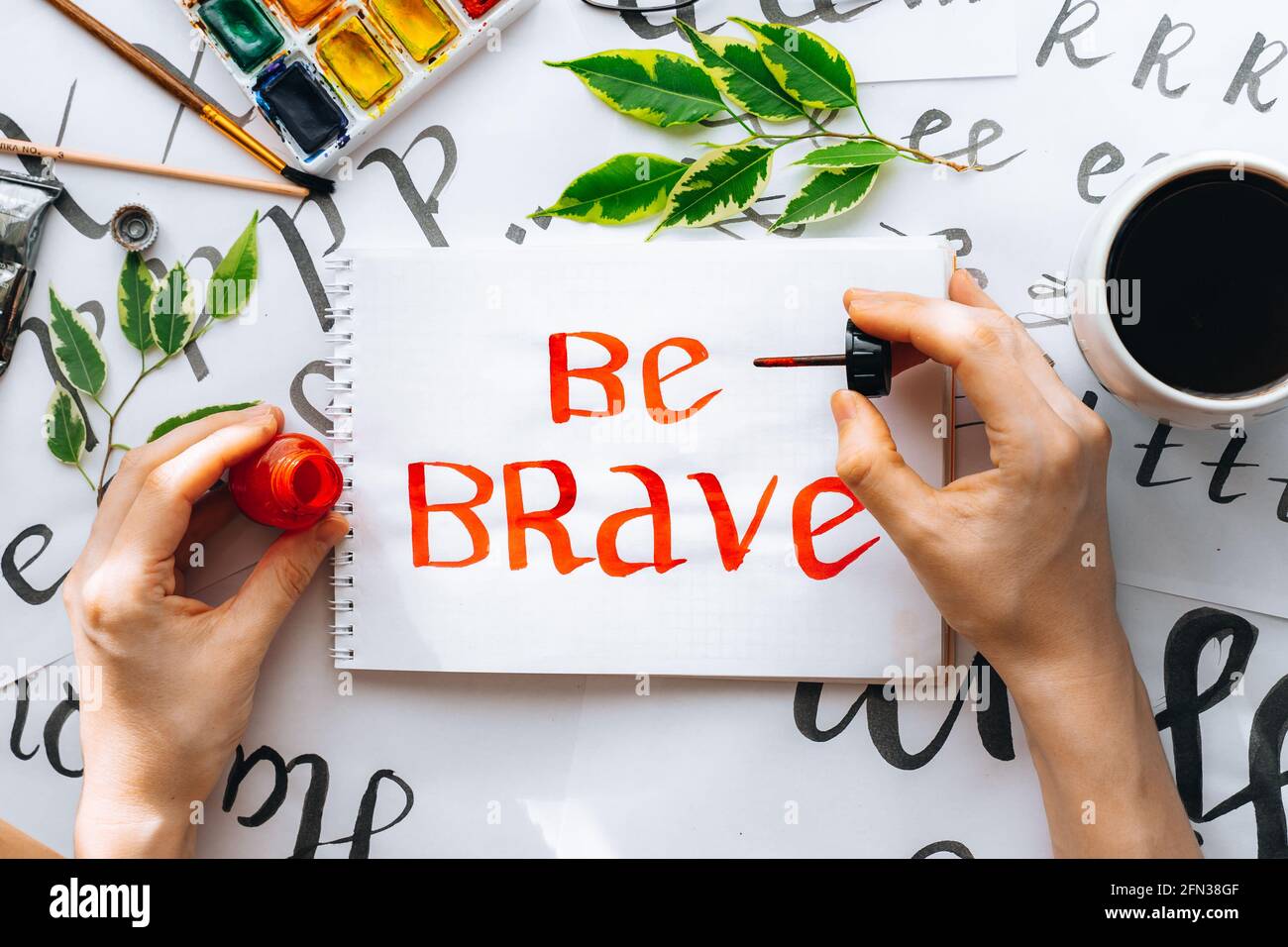 Overhead-Ansicht auf männlichen Mann Hände Kalligraphie Blätter, Schreibfedern, Papier, Tinte rote Stifte.Handwerk, Hobby. Lettering Workshop.Flat Lay Motivationsschreiben Worte Quo Stockfoto