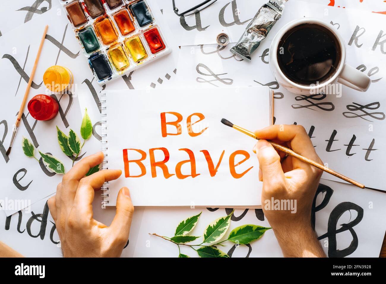 Overhead-Ansicht auf männlichen Mann Hände Kalligraphie Blätter, Schreibfedern, Papier, Tinte rote Stifte.Handwerk, Hobby. Lettering Workshop.Flat Lay Motivationsschreiben Worte Quo Stockfoto