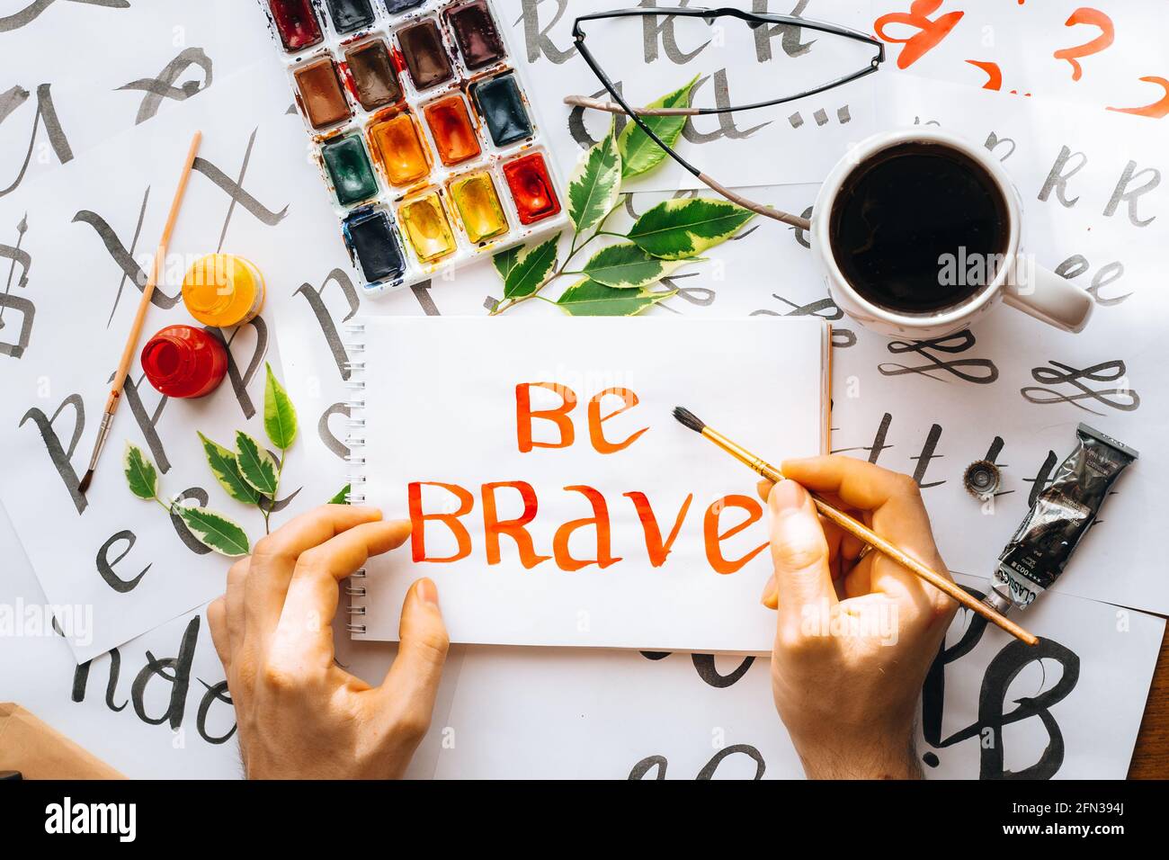 Overhead-Ansicht auf männlichen Mann Hände Kalligraphie Blätter, Schreibfedern, Papier, Tinte rote Stifte.Handwerk, Hobby. Lettering Workshop.Flat Lay Motivationsschreiben Worte Quo Stockfoto