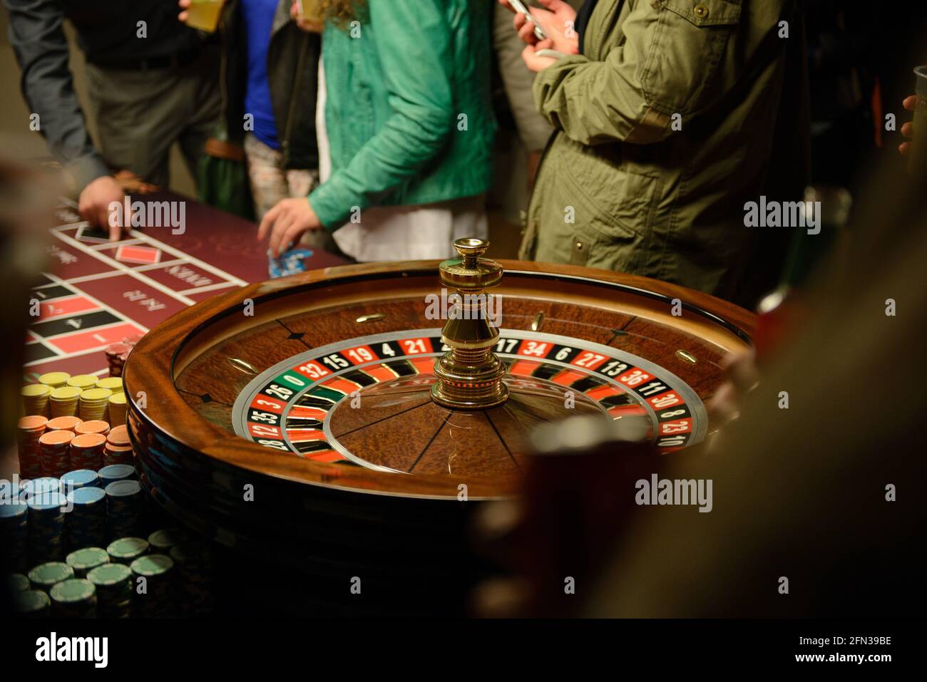 Roulette dreht sich am Tisch im Casino, Menschen setzen Wetten Stockfoto