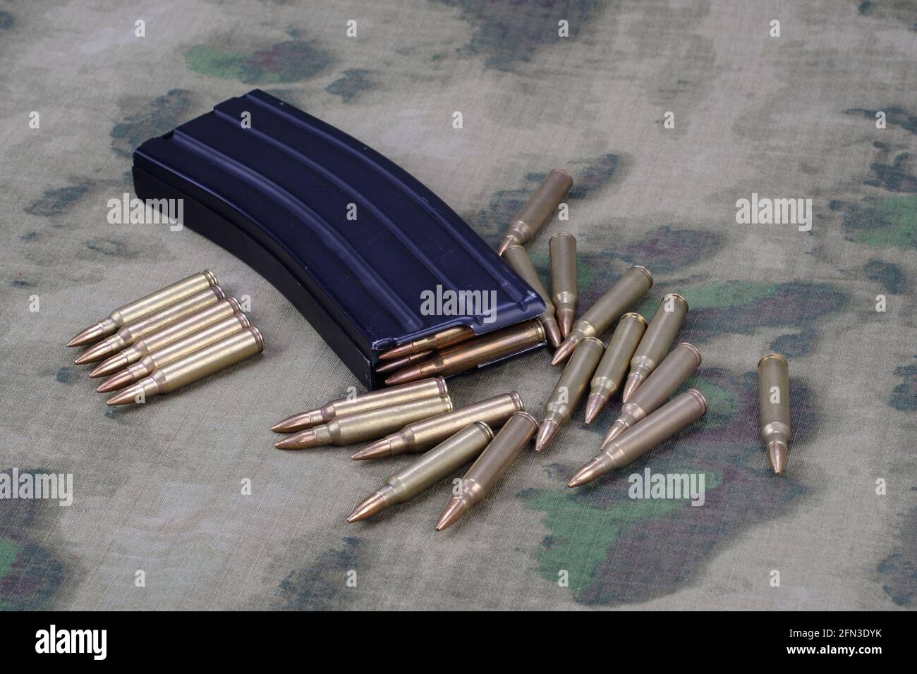 5.56mm-Munitionskugel mit Vollmetallmantel und Magazin an Camouflage uniform Hintergrund Stockfoto