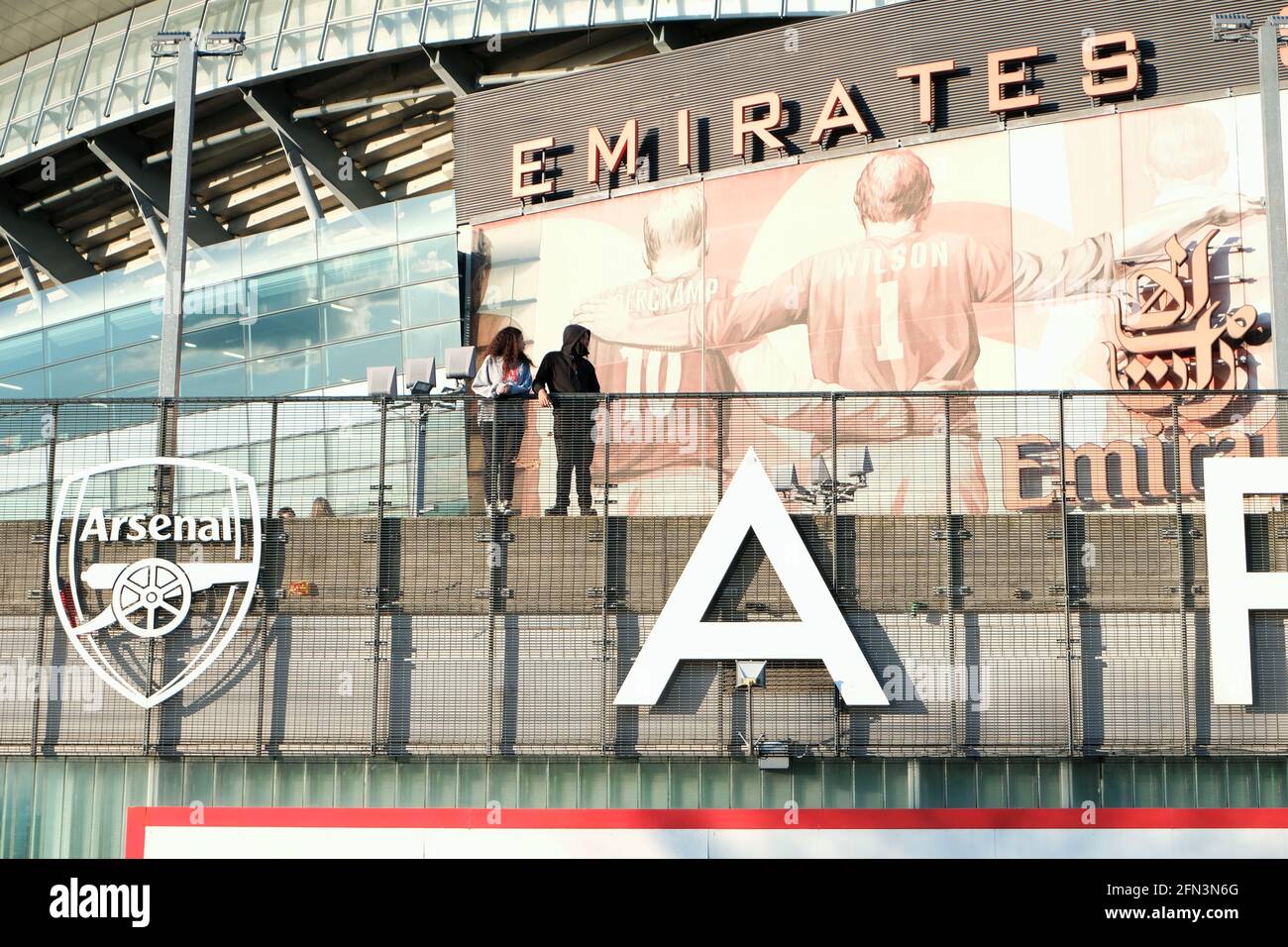 Zwei Personen stehen vor dem Emirates-Fußballstadion, in dem der Arsenal-Fußballverein in Highbury, London, beheimatet ist. Stockfoto