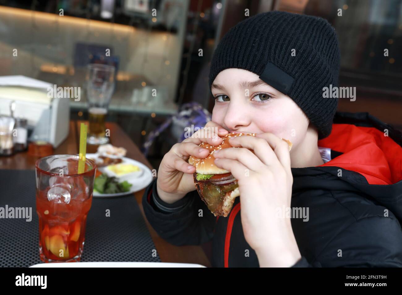 Kinder essen Burger auf der Restaurantterrasse im Frühling Stockfoto