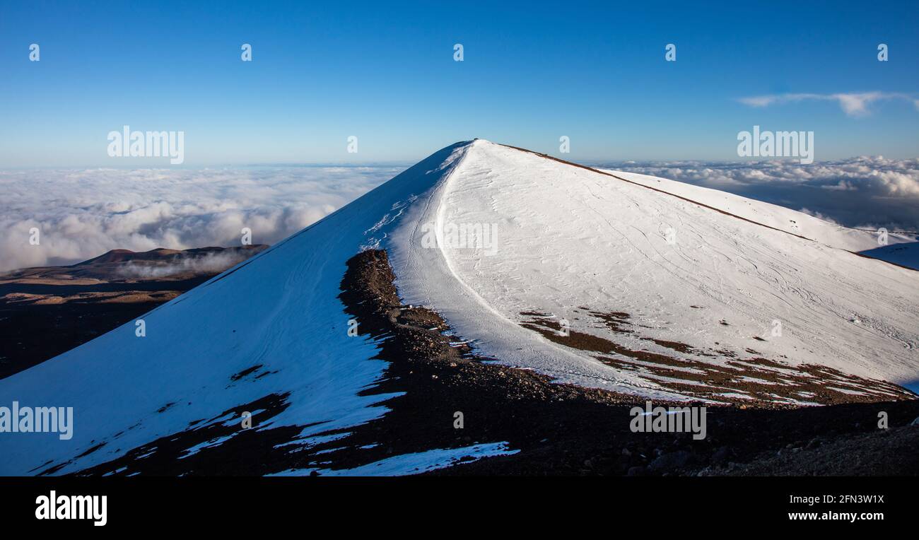 Der schneebedeckte Gipfel des Mauna Kea, der größte Schildvulkan der Welt und der höchste Berg der Welt, wenn man ihn von seiner Basis aus misst. Auf dem großen Ich Stockfoto