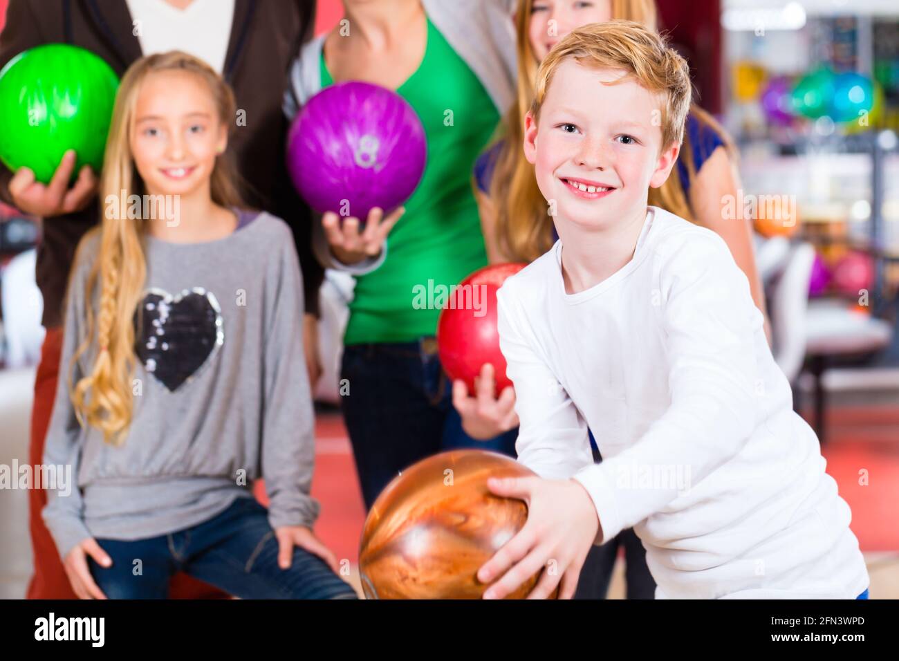 Eltern spielen mit Kindern zusammen im Bowling-center Stockfoto