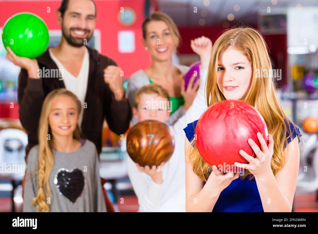 Eltern spielen mit Kindern zusammen im Bowling-center Stockfoto