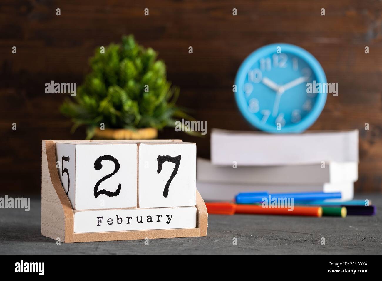 Februar. Februar 27 Holzwürfelkalender mit unscharfen Objekten auf dem Hintergrund. Stockfoto