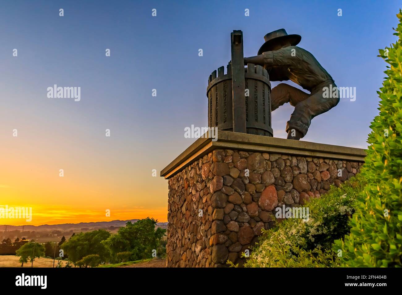Traubenbrecher-Statue und Landschaft mit Hügeln und Tälern bei Sonnenuntergang am südlichen Eingang zum Napa Valley, Kalifornien, USA Stockfoto