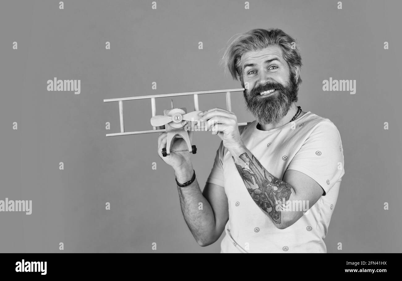 Das ist erst der Anfang. Flugreisen. Transportkonzept. Kindheitstraum. Aviator bärtiger Hipster-Mann. Spielzeug aus einem hölzernen Flugzeug. Fliegen Sie mit dem Flugzeug. Buchen Stockfoto