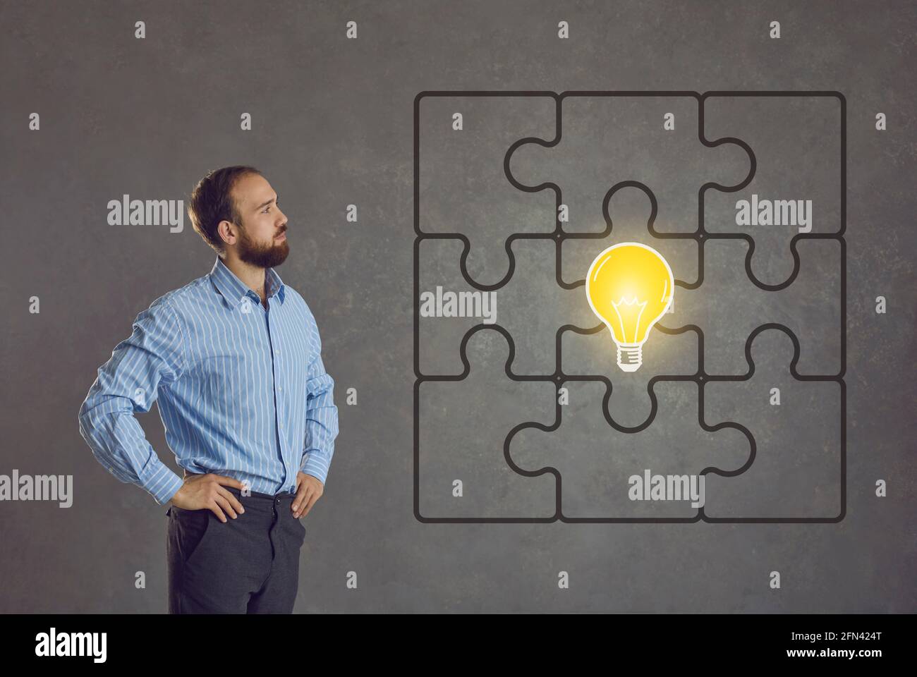 Mann betrachtet ein komplettes Puzzle mit einem hellen Idea Glühbirne in der Mitte Stockfoto