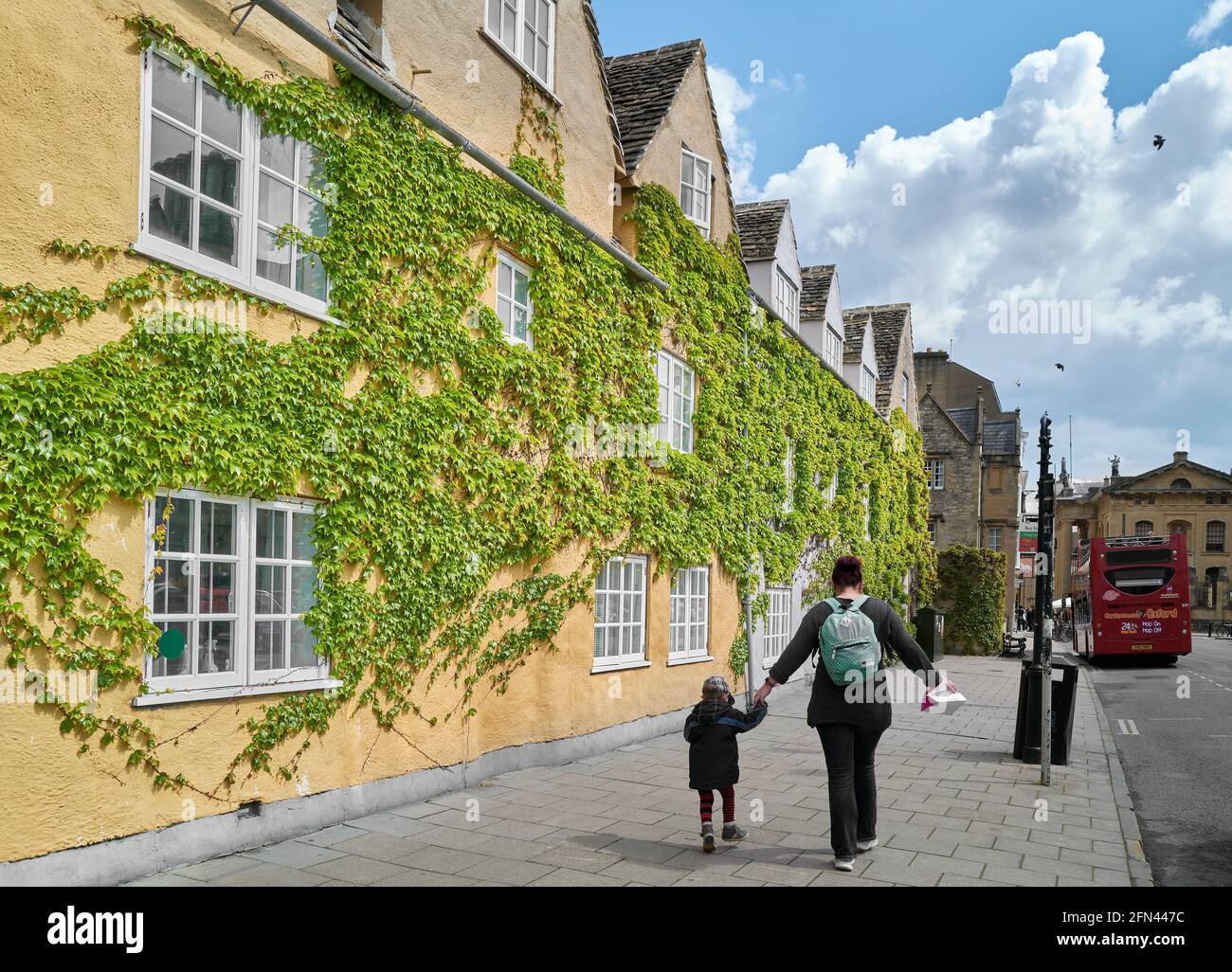 Mutter und Kind gehen an der efeubedeckten Wand des Trinity College der Universität Oxford, England, vorbei. Stockfoto
