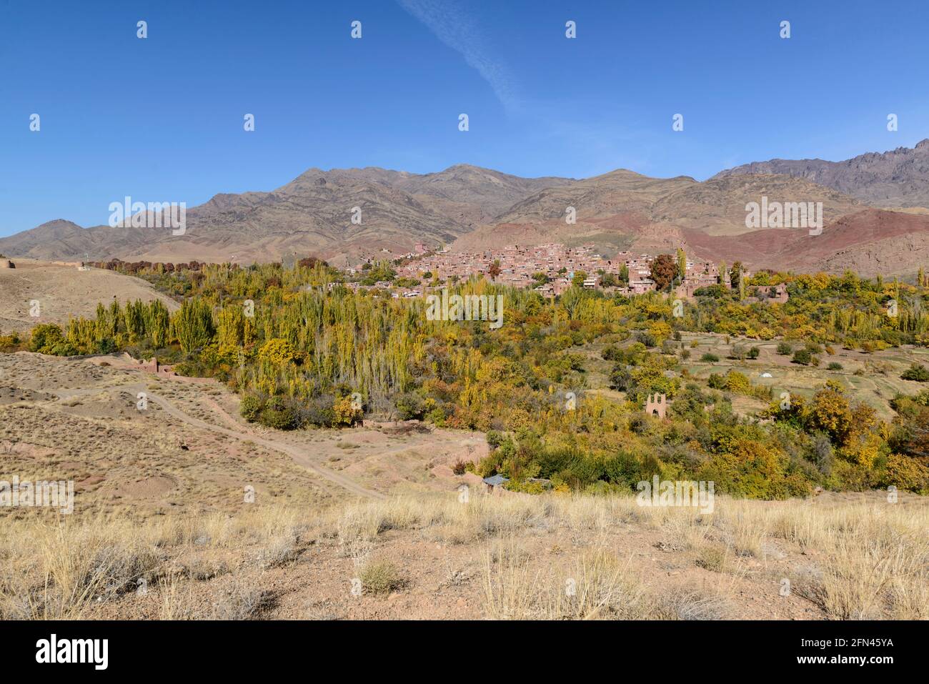 Bäume in Herbstfarben und das alte Dorf Abyaneh im Hintergrund, Provinz Isfahan, Iran. Stockfoto