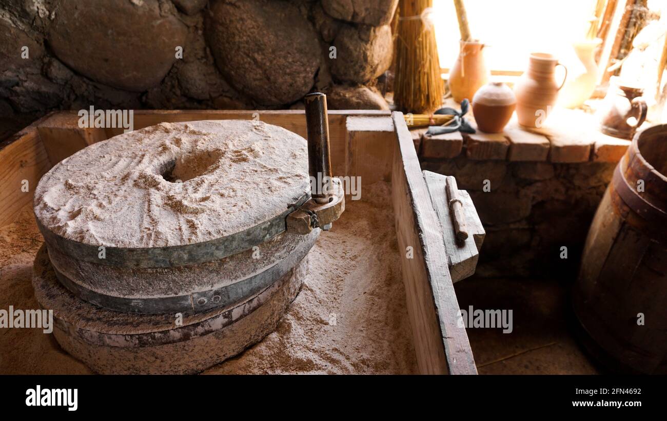 Eine alte Handmühle aus Steinen und Holz. Mehlschleifvorrichtung. Authentisches Kunsthandwerk Stockfoto