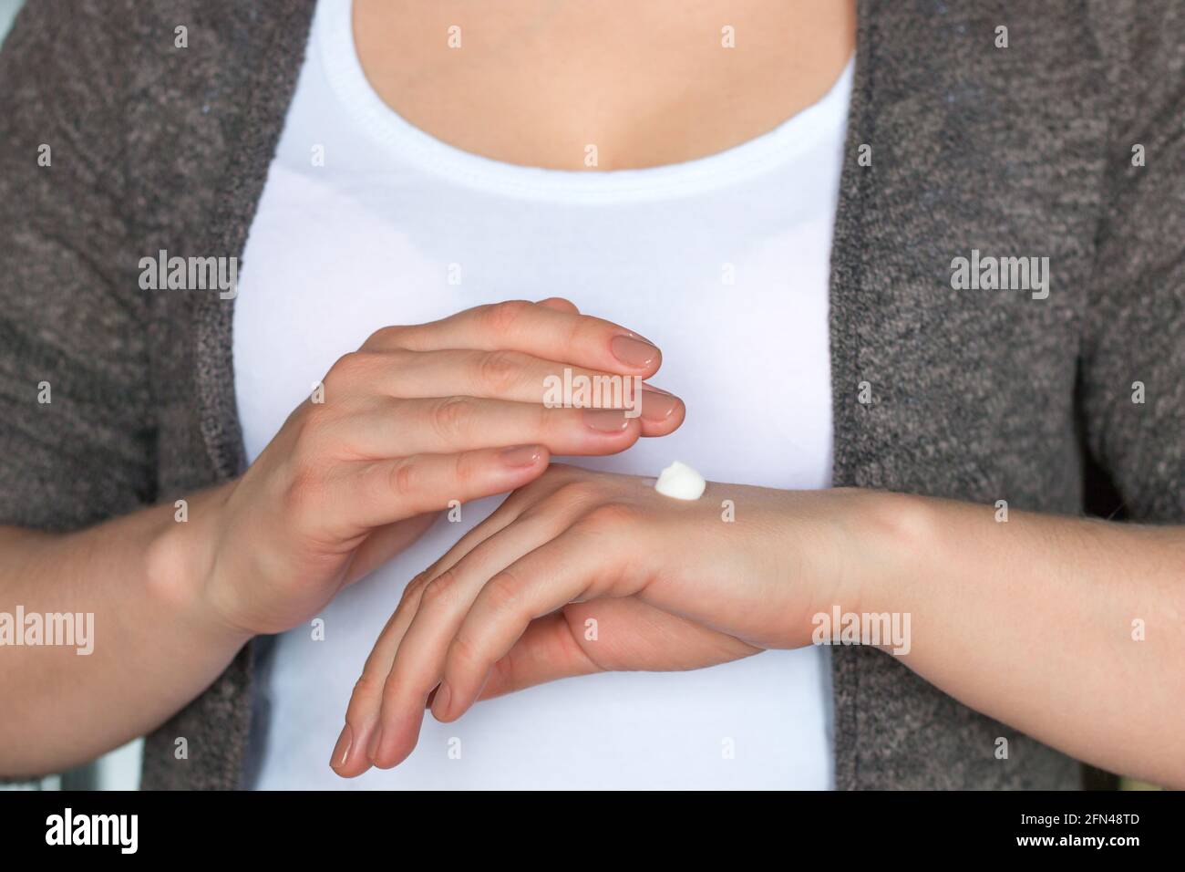 Junge Frau, die feuchtigkeitsspendende Handcreme anwendet Stockfoto