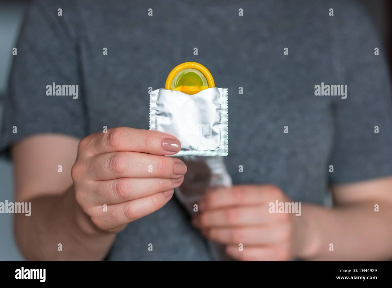 Junge Frau mit gelbem Kondom Stockfoto