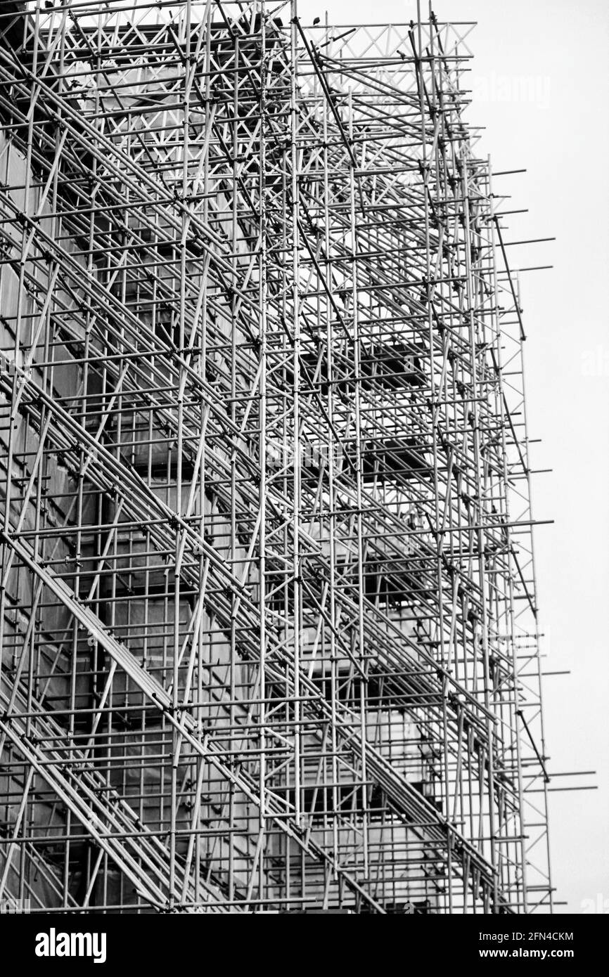 Ein riesiges Gerüst zur Renovierung der Fassade eines Schlosses. Dichte Struktur von Rohren und Masten. Architektur, Restaurierung und laufende Arbeiten. Stockfoto