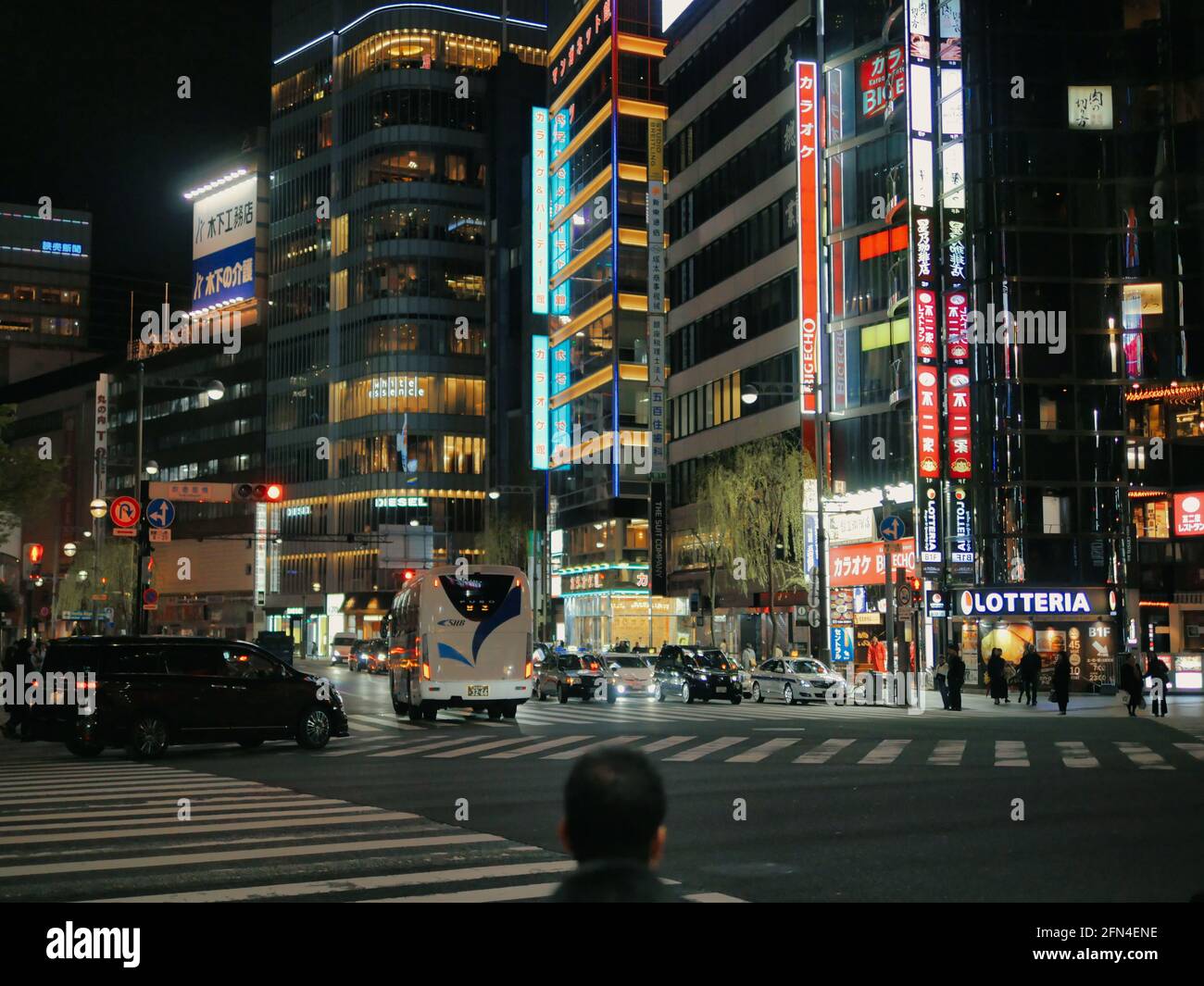 Nachtstraßen des Distrikts Kabukicho, Shinjuku. Kopf eines Japaners in der Mitte, der die neonbeleuchteten Wolkenkratzer anschaut. Modernes Leben und Industrie. Stockfoto