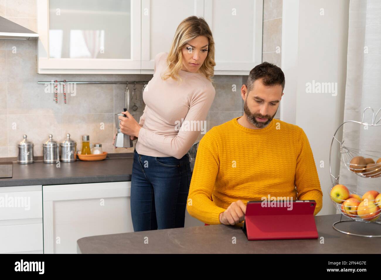 Verdächtige Frau findet ihren Mann entdeckt etwas Schlechtes.. Intrigierte Frau in der Küche bereitet Kaffee hinter ihrem betrügenden Ehemann zu. Stockfoto