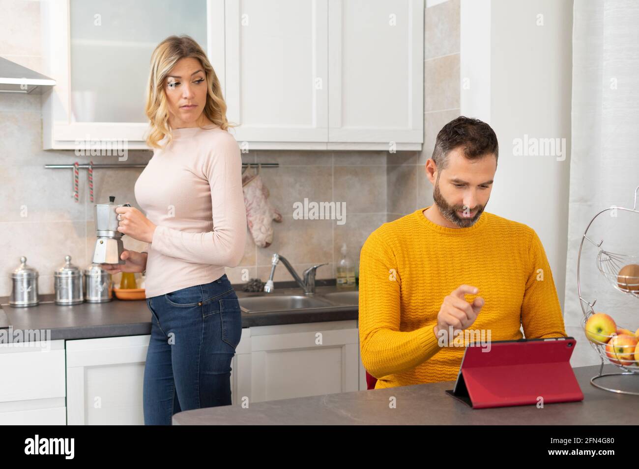 Verdächtige Frau findet ihren Mann entdeckt etwas Schlechtes.. Intrigierte Frau in der Küche bereitet Kaffee hinter ihrem betrügenden Ehemann zu. Stockfoto