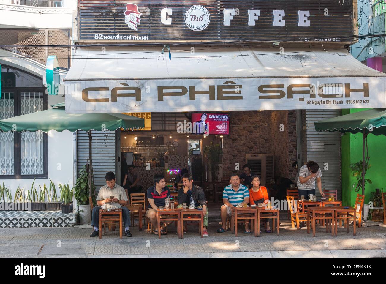 Vietnamesische Freunde sitzen im Freien vor dem Café Ca Phe Sach, Da Nang, Vietnam Stockfoto