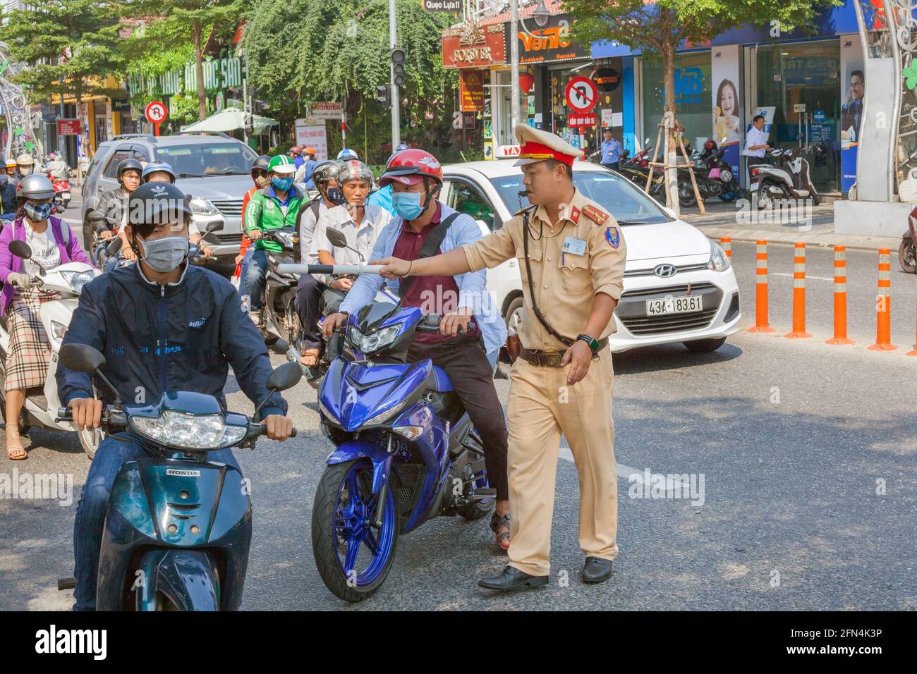 Vietnamesischer Verkehrspolizist mit Pfeife im Mund zieht wegen Verkehrsverletzung einen Mann auf dem Motorrad an, Da Nang, Vietnam Stockfoto