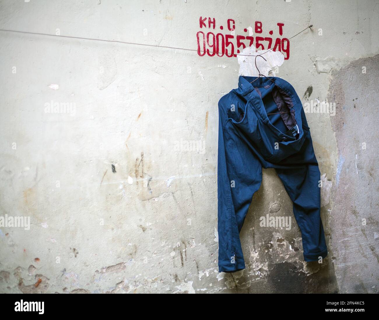 Ein Paar marineblaue Jeans, die an der Linie unter der Telefonnummer von KHCBT (Building Services and Demolition), Da nang, Vietnam, hängen Stockfoto