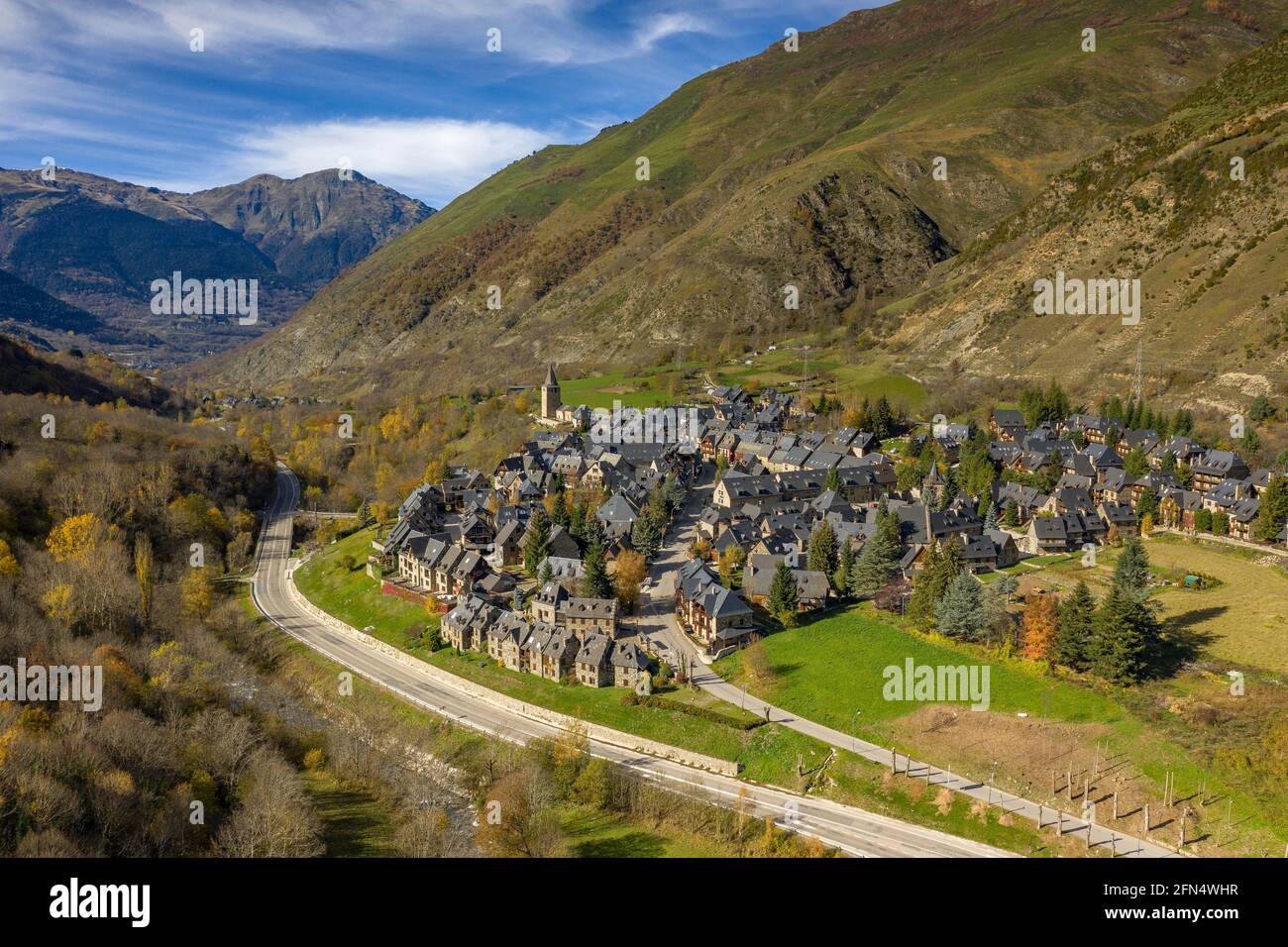 Luftaufnahme des Dorfes Garòs und der umliegenden Wälder im Herbst (Aran-Tal, Katalonien, Spanien, Pyrenäen) ESP: Vista aérea de Garòs y bosques cercanos Stockfoto