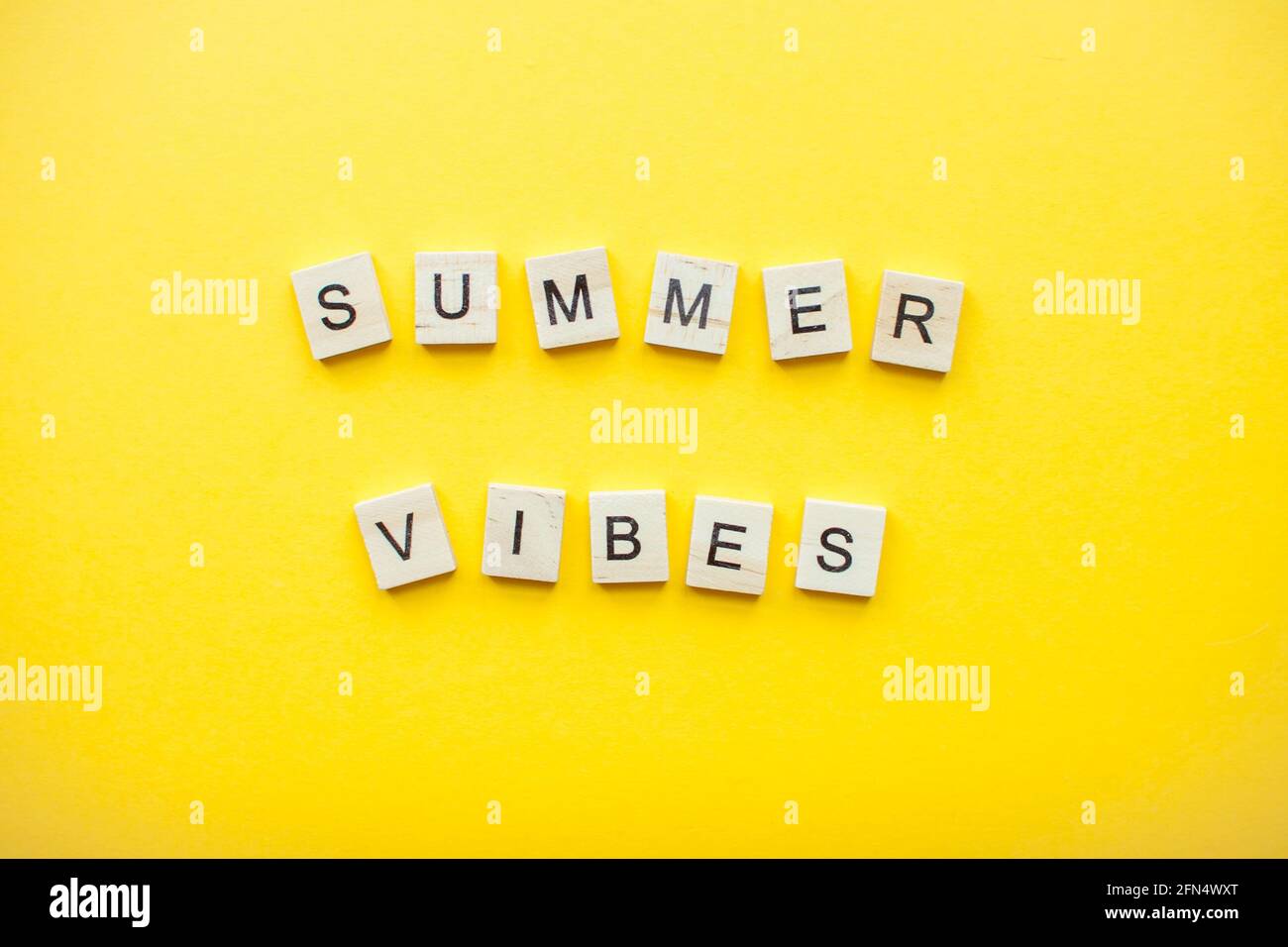 Die Inschrift aus Holzwürfeln Sommer vibriert auf einem hellen Gelber Hintergrund Stockfoto