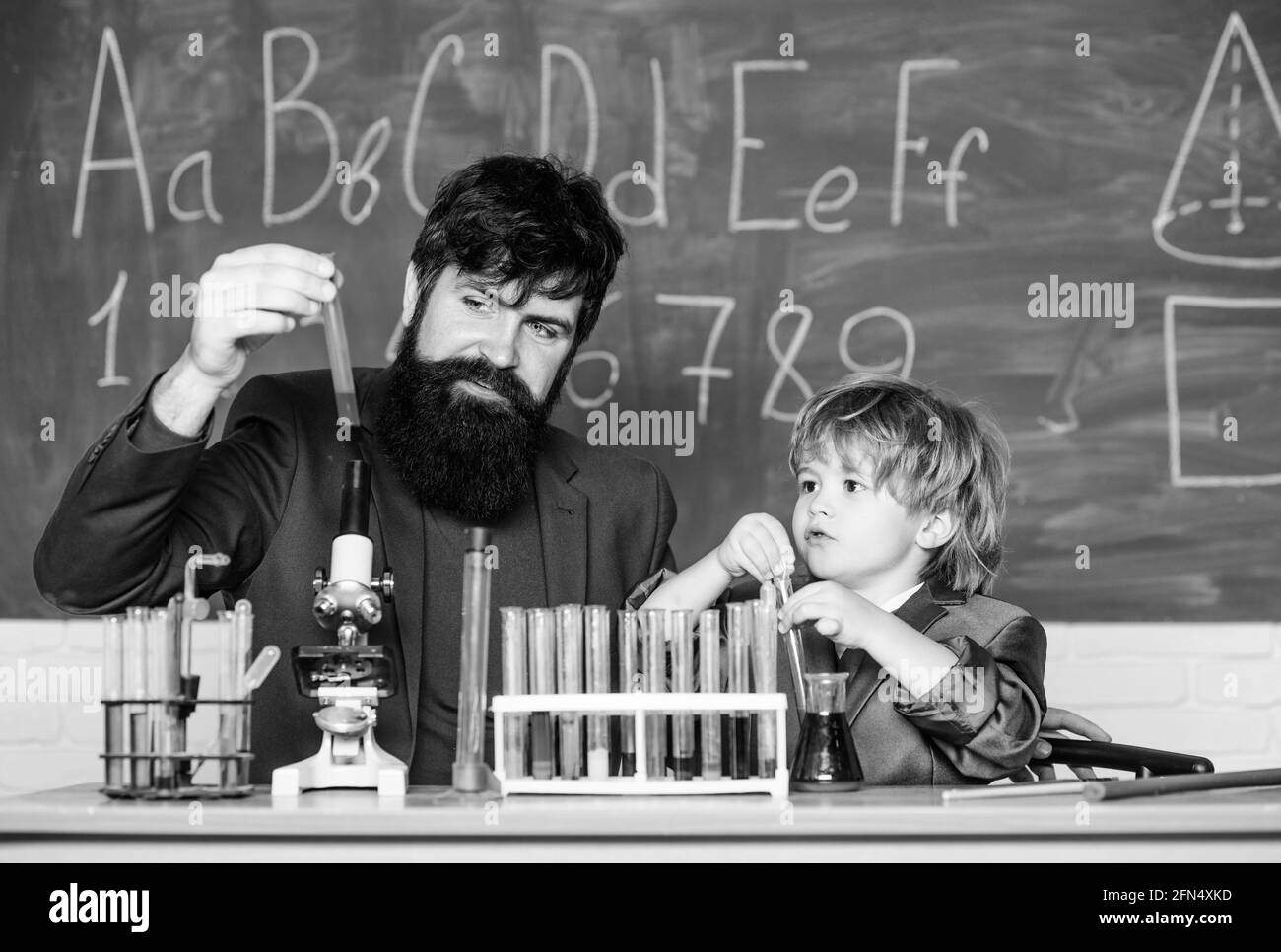 Kleiner Junge mit Lehrer Mann. Der Biologe führt Experimente durch, indem er Verbindungen synthetisiert. Zurück zur Schule. Sohn und Vater in der Schule Stockfoto