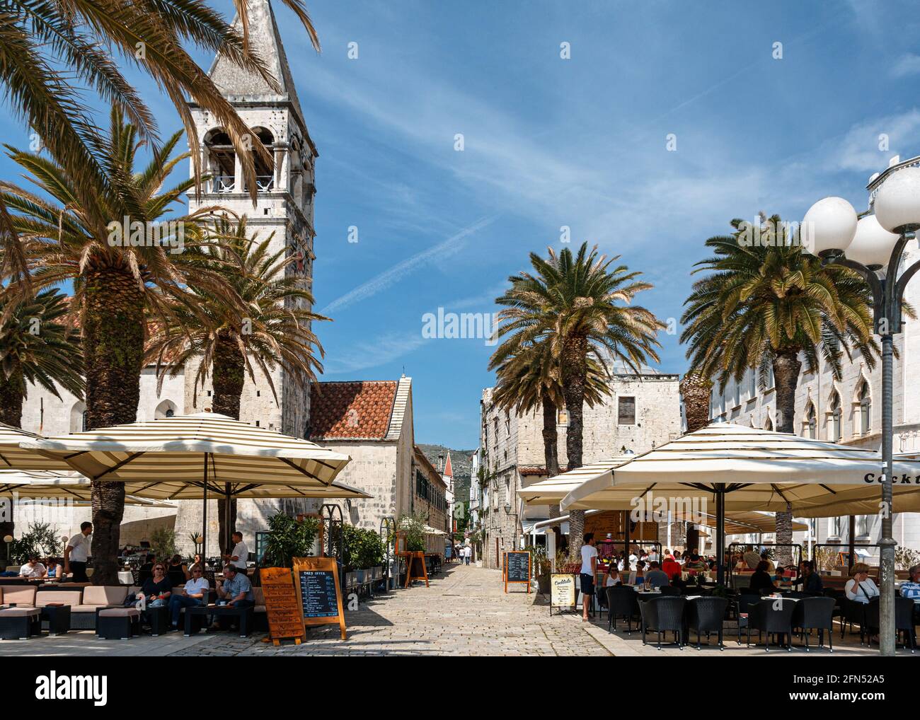 Café-Terrassen mit Touristen auf der Promenade in Trogir, Kroatien Stockfoto