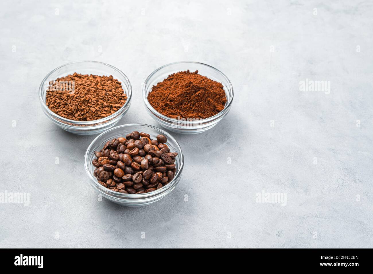 Drei Tassen mit verschiedenen Kaffeesorten auf grauem Hintergrund. Seitenansicht, Kopierbereich. Stockfoto