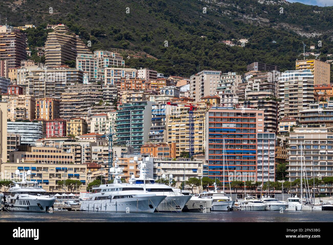 Hügel und Gebäude an der Grenze zum Jachthafen und Bootshafen in Monte Carlo, Monaco an der französischen Riviera. Stockfoto