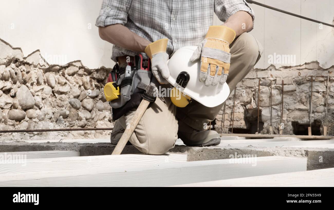 Bauarbeiter mit Werkzeugtasche trägt Handschuhe und hält Helm in den  Händen, Projektplan für Hausrenovierung, Arbeitskonzept, Nahaufnahme von  Balken von Gebäuden Stockfotografie - Alamy