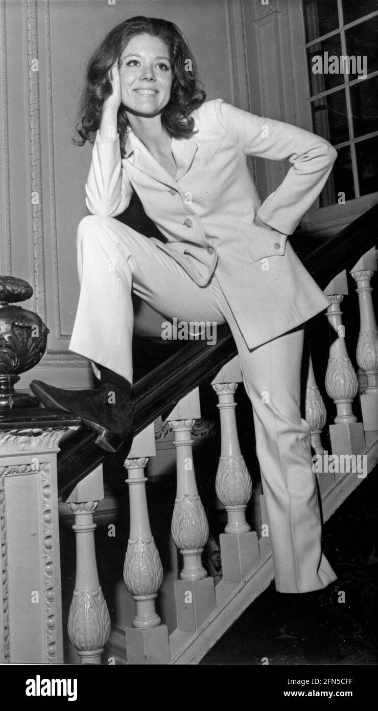 Die Schauspielerin Diana Rigg, berühmt für ihre Rolle in den 1960er Jahren als Emma Peel in der Fernsehserie The Avengers, posiert in einem weißen Hosenanzug auf Treppen in den 1960er Jahren Stockfoto