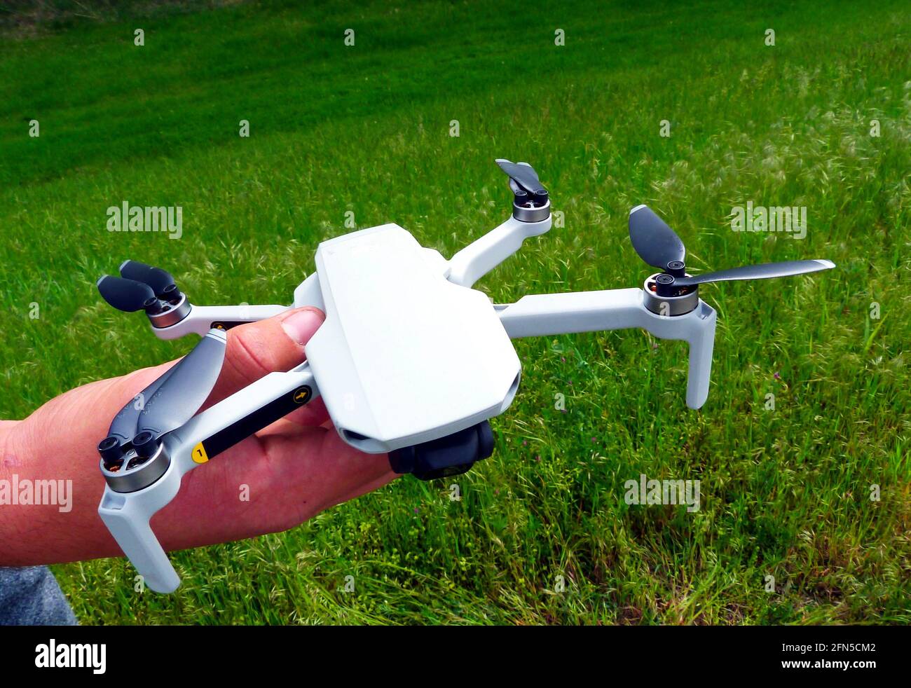 Kleine weiße Kamera-Drohne in männlicher Hand gehalten. Schwarze Propeller. Nahaufnahme. Noch bewegungslose Propeller. Technologie und Luftaufnahmen Stockfoto