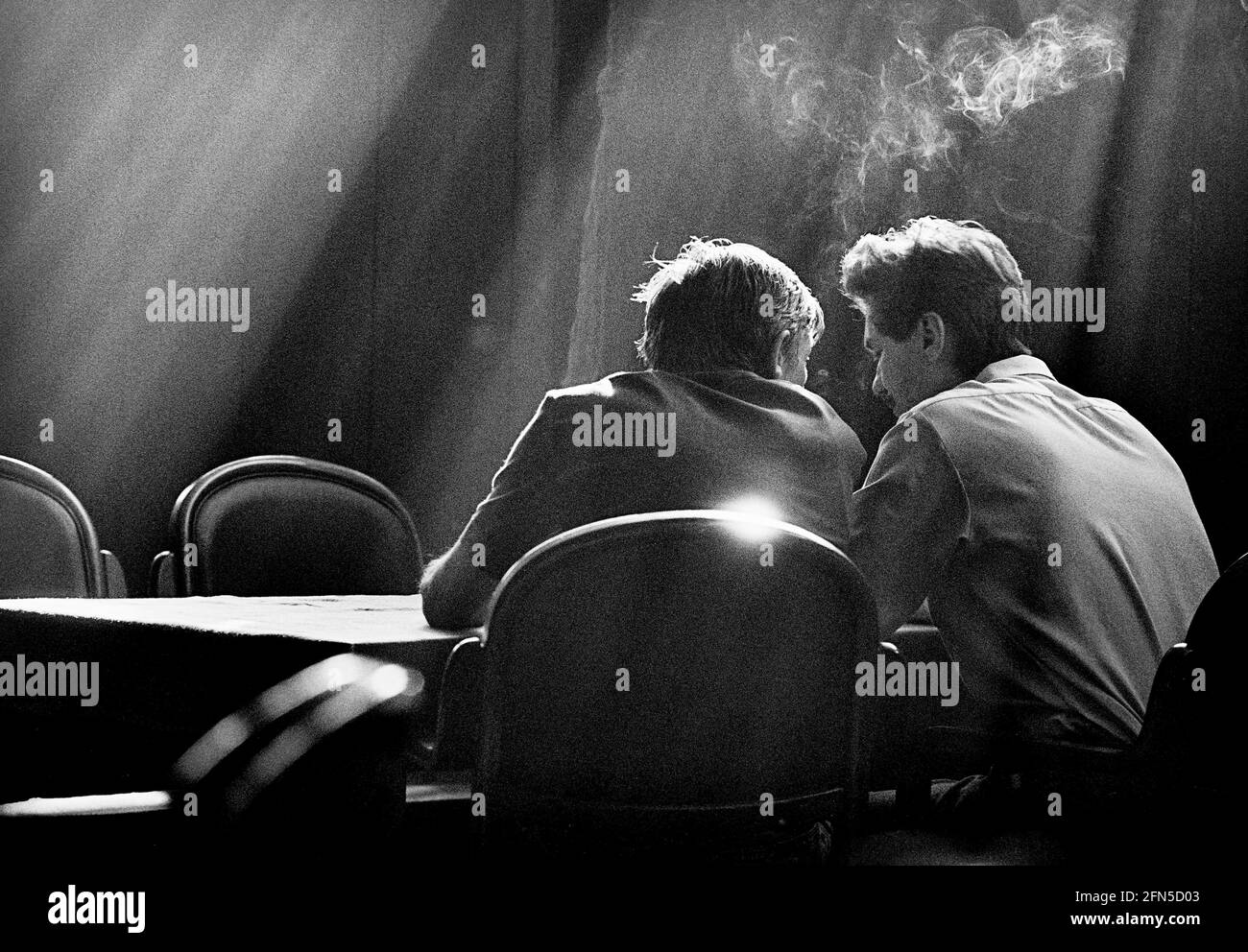 Umgeben von fallendem Licht sitzen zwei Männer in einem dunklen Pub in Kiew. Sie reden, rauchen und trinken. 02.09.1991 - Christoph Keller Stockfoto
