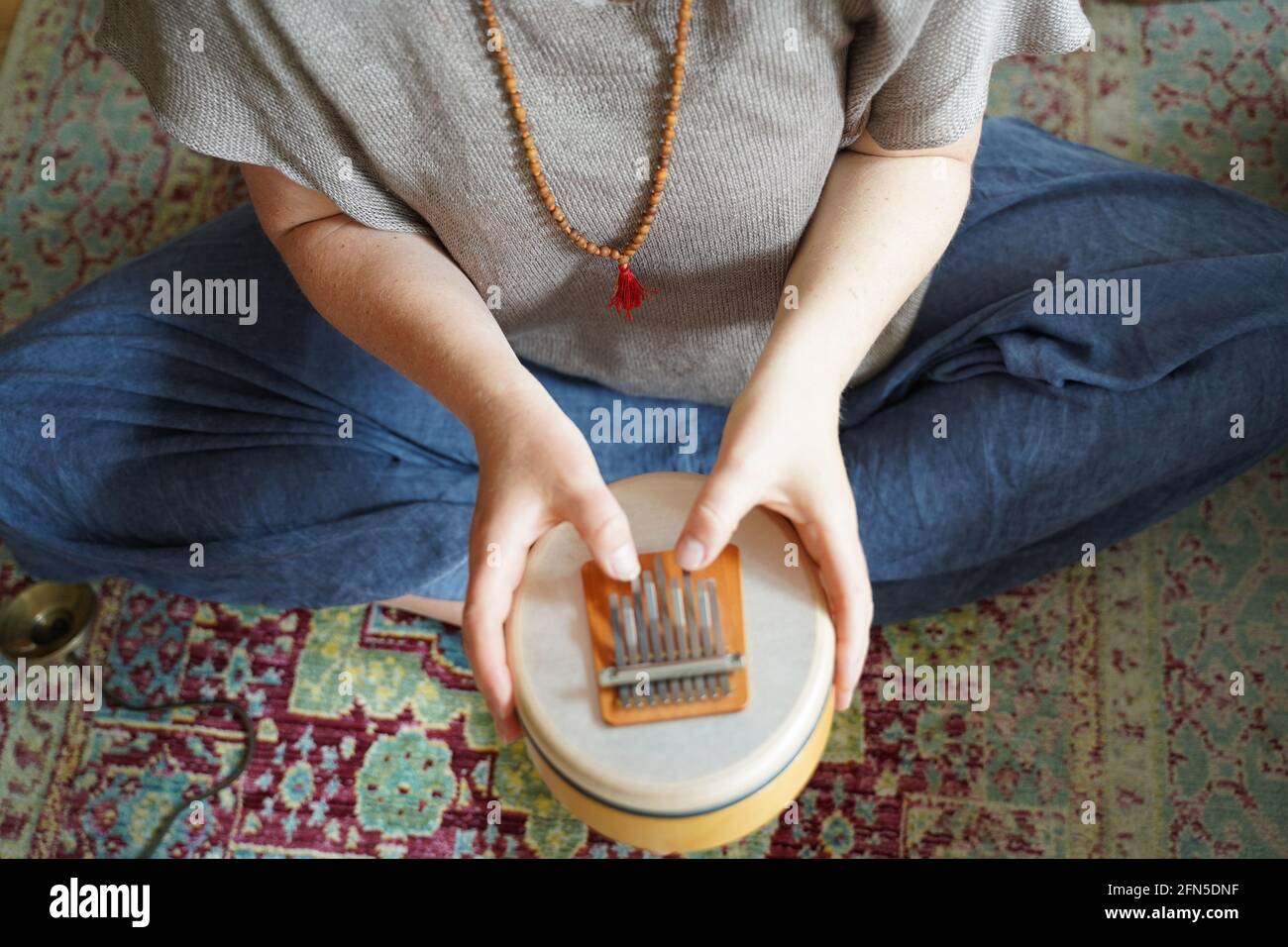 Frau, die ein Klangheilungsinstrument Sansula für die Klangheilung hält und spielt Stockfoto