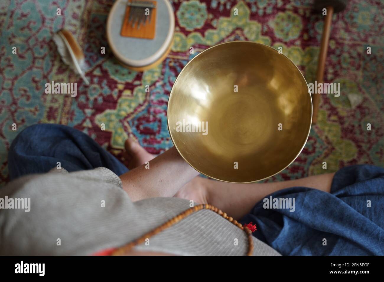 Kaukasische Frau, die eine tibetische Klangschale in der Hand hält, um eine Klangtherapie zu erhalten Stockfoto