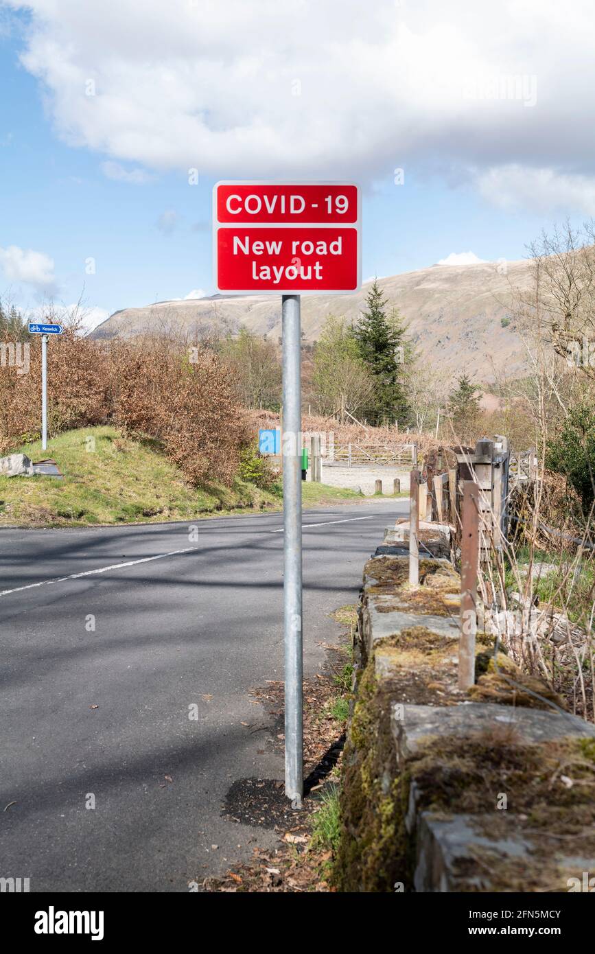 Covid 19-Schild warnt vor neuer Straßengestaltung am Thirlmere-Staudamm, Lake District, Großbritannien. Stockfoto