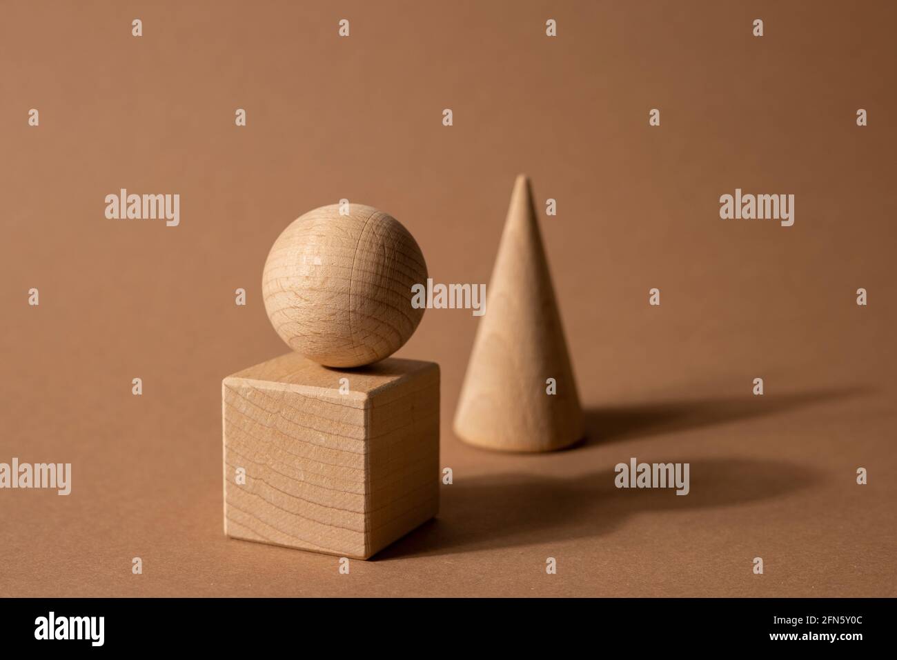 Holzspielzeug-Kindersorter mit kleinen Holzdetails in Form von geometrischen Formen Rechteck, Quadrat, Dreieck auf braunem Hintergrund, Figurenkonzept mit dunklen Schatten Stockfoto