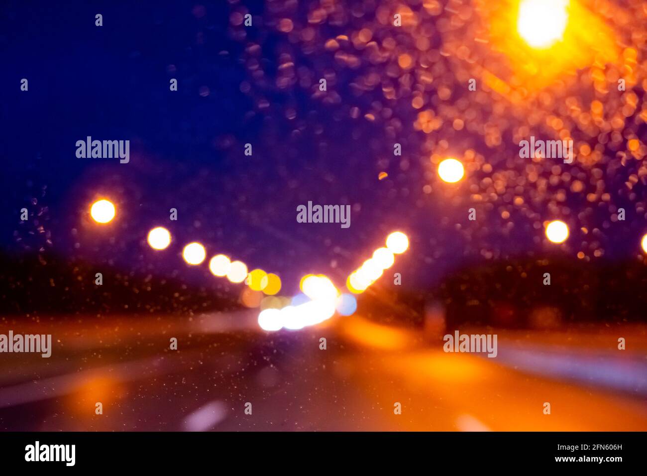 Nasse Spur in der Nacht mit der Aussicht auf Beleuchtung Lichter entlang der Straße in einer regnerischen Nacht, verschwommener Hintergrund, kopieren Raum Stockfoto