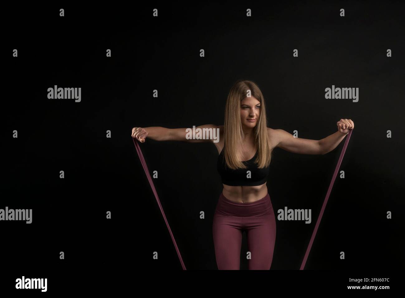 Fitness-Mädchen trainieren Schultern mit elastischem Band Stockfoto